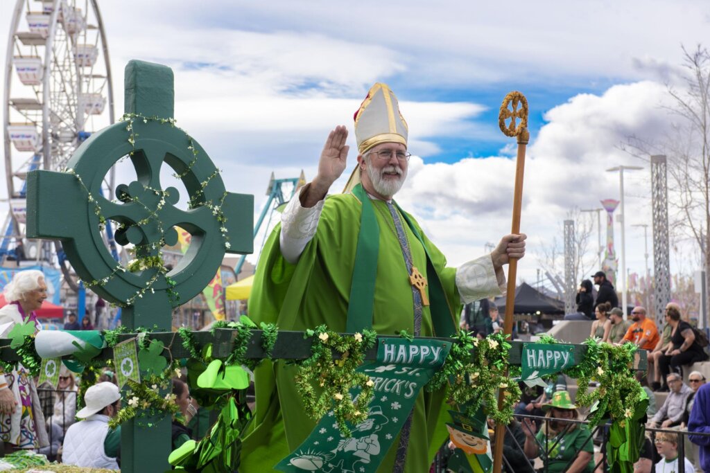 A bearded man dressed in green religious robes and hat on a Happy Saint's Patrick Day float.