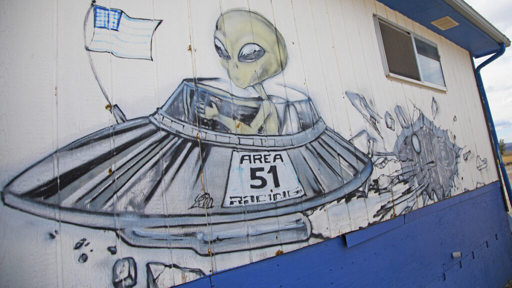 Mural on the side of a building depicting an alien driving a saucer labeled Area 51 Racing with a checkered flag.