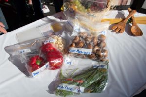 An image of multiple bags of vegetables sitting on a table with a white table cloth