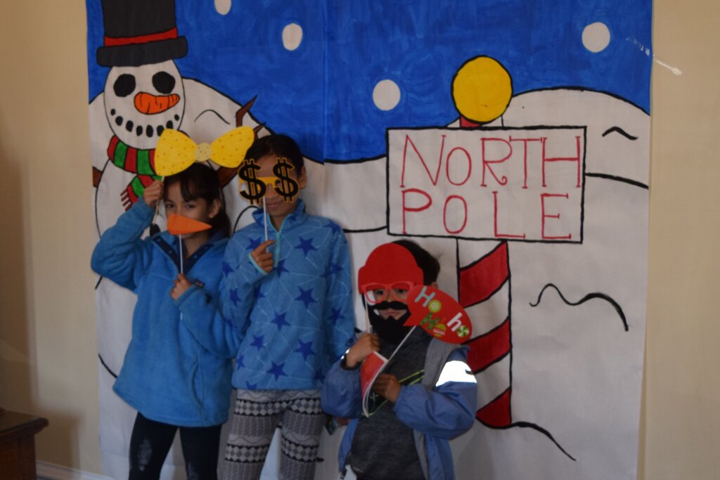 Two children in front of North Pole photo booth backdrop.
