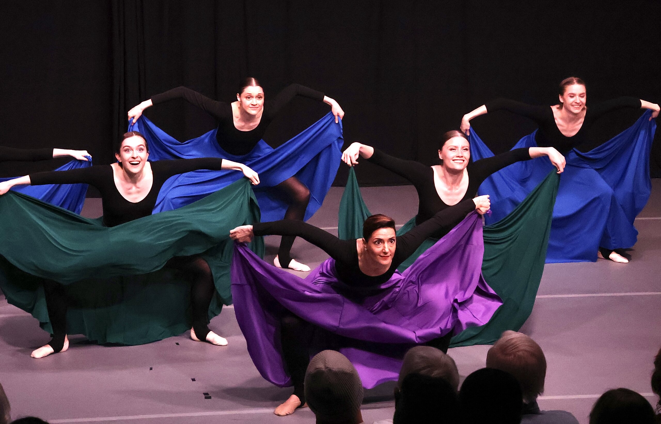 Five dancers in purple, green and blue skirts dramatically perform.