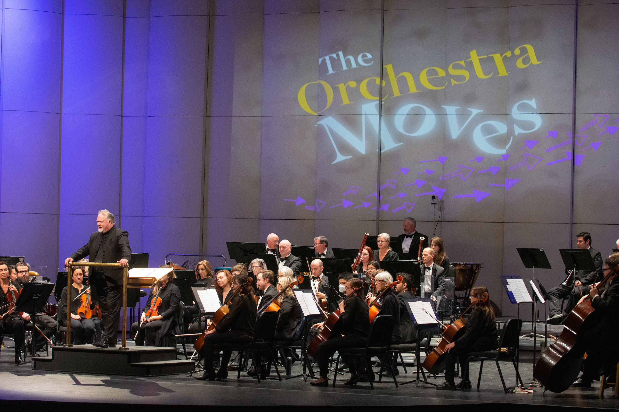 The Reno Phil plays on stage with a background graphic of Orchestra Moves