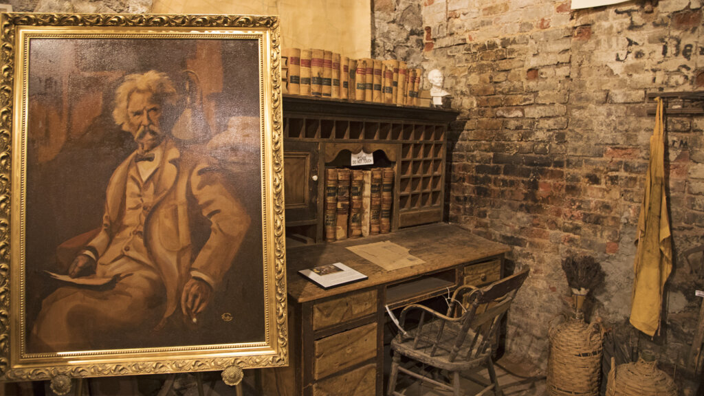 A frame painting of Mark Twain next to a desk in the Territorial Enterprise in Virginia City. (Photo provided by Travel Nevada/Photo by Sydney Martinez)