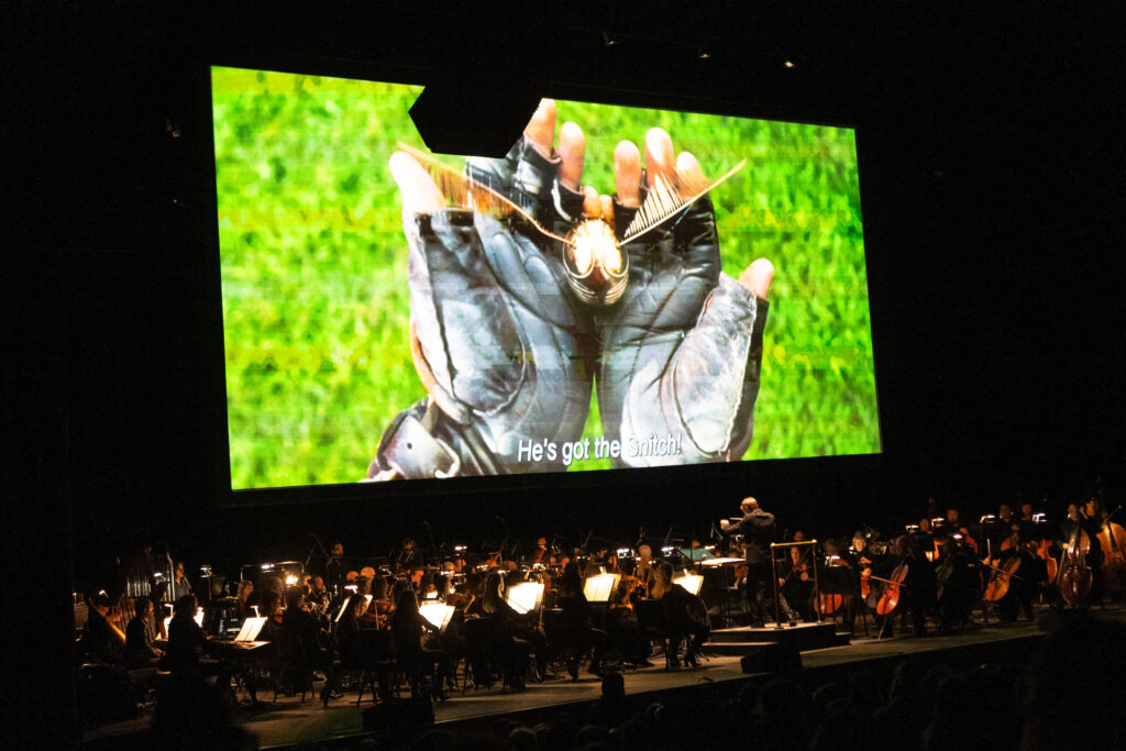 Harry Potter movie plays on screen above the orchestra.