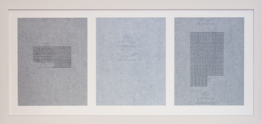 Three pieces of light blue paper with faint horizontal lines and watermarks are displayed in a white frame, arranged side by side. The center paper shows a circular watermark with text and a crown.