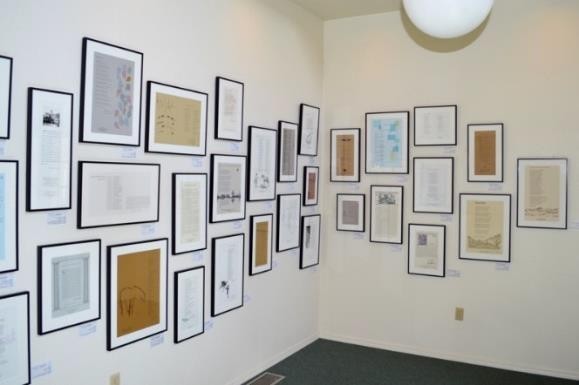 Framed documents and illustrations cover two cream-colored gallery walls in a corner display.