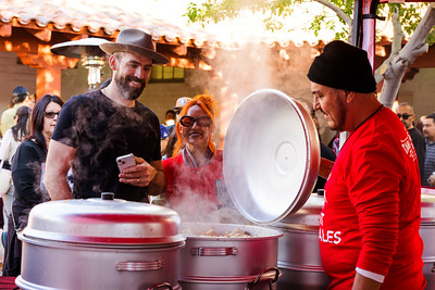 Attendees at the Tamale Fest visit a food vendor as he raised a lid on a large pot.