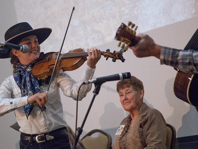 cowboy poetry a woman in cowboy clothing performs on the violin