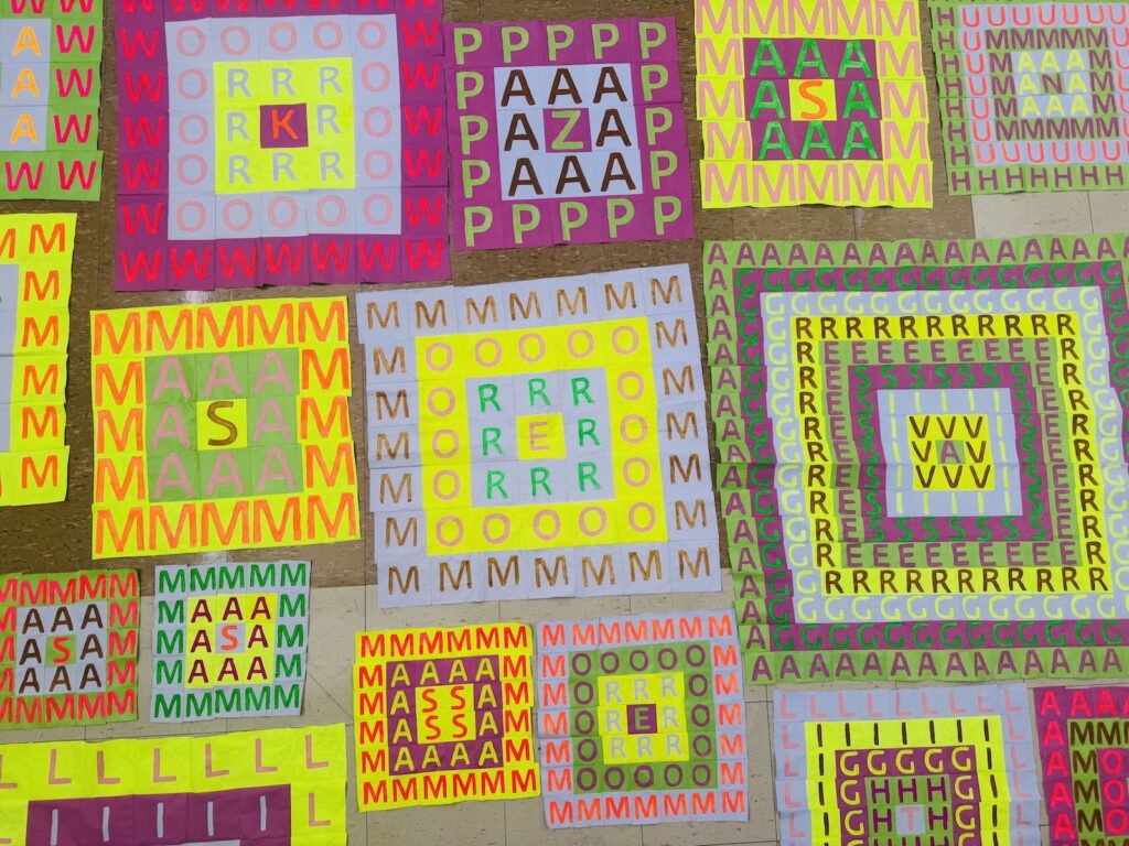 A collection of square paper mosaics made of small letter cutouts arranged in concentric, multicolored patterns.