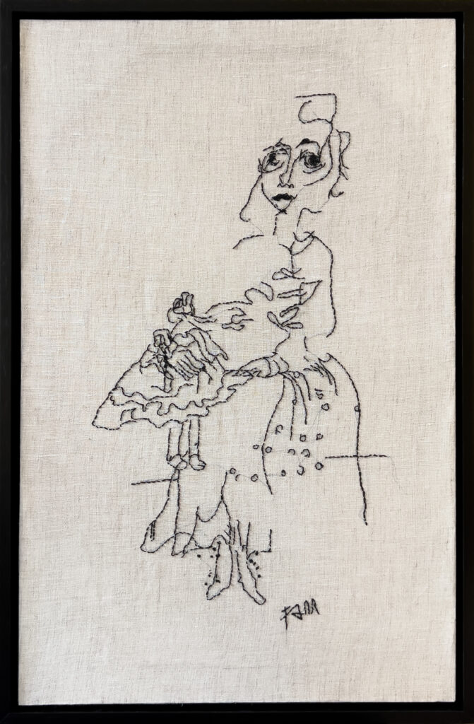 Black thread embroidery on beige fabric depicts a loosely sketched woman sitting with a small, elaborately dressed figure on her lap, framed in black. The lines are expressive and minimalist.